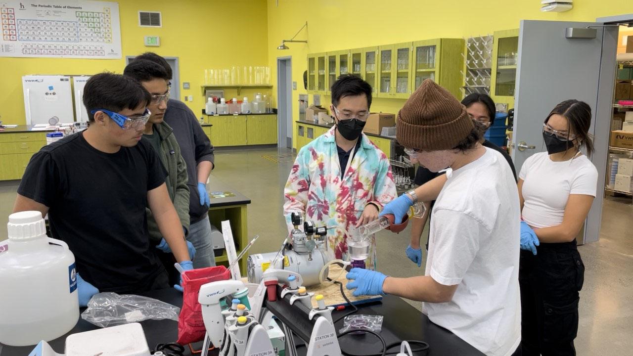 South City High biotech teacher Rocky Ng helps students grow bacterial cultures.